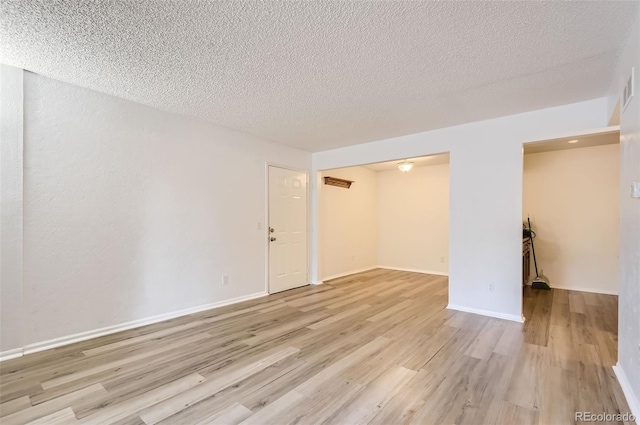 empty room with light hardwood / wood-style floors and a textured ceiling