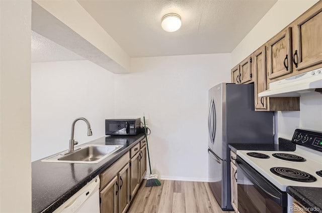 kitchen featuring light wood-type flooring, white appliances, sink, and a textured ceiling