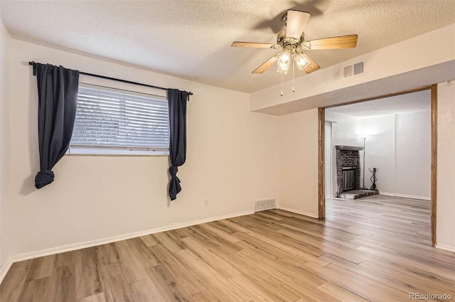 empty room with a textured ceiling, ceiling fan, and light hardwood / wood-style flooring