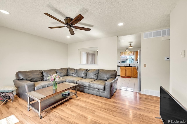 living area featuring visible vents, light wood-style floors, and a ceiling fan