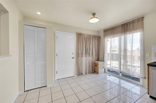 unfurnished bedroom featuring light tile patterned floors, a closet, baseboards, and access to outside