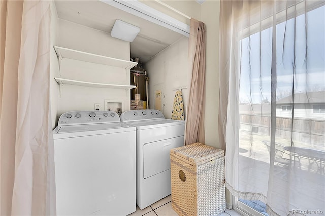 clothes washing area featuring washer and dryer, laundry area, light tile patterned floors, and water heater