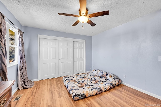 bedroom featuring light wood-style floors, visible vents, a closet, and baseboards