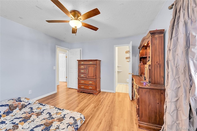 bedroom featuring light wood-style flooring, a ceiling fan, baseboards, and a textured ceiling