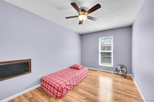 bedroom with a textured ceiling, baseboards, and wood finished floors