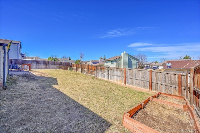 view of yard with a vegetable garden, a residential view, and a fenced backyard