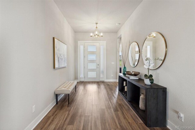 entryway with an inviting chandelier, baseboards, and wood finished floors