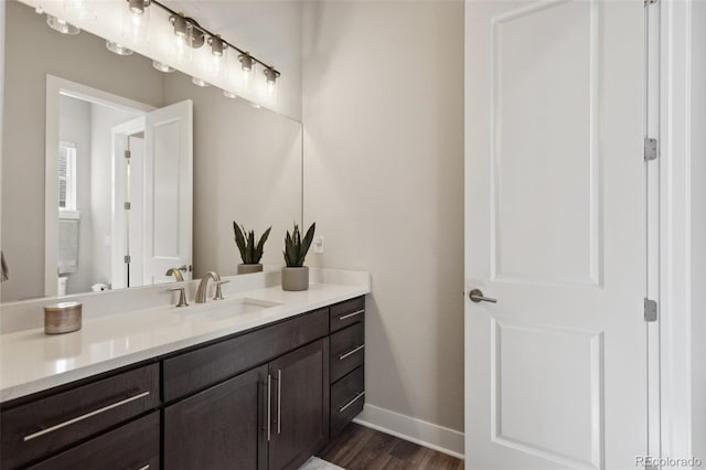 bathroom featuring baseboards, wood finished floors, and vanity