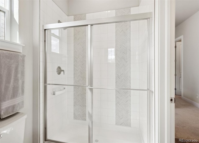 bathroom with toilet, baseboards, and a shower stall