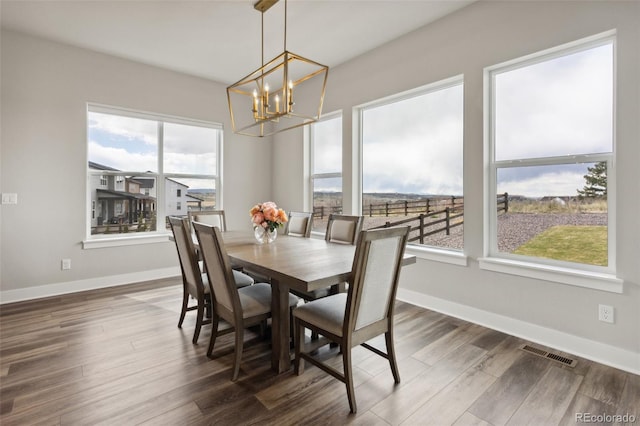 dining area featuring visible vents, a notable chandelier, a wealth of natural light, and dark wood-style floors