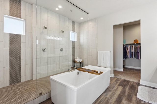 full bath with a walk in shower, recessed lighting, wood finished floors, and a soaking tub