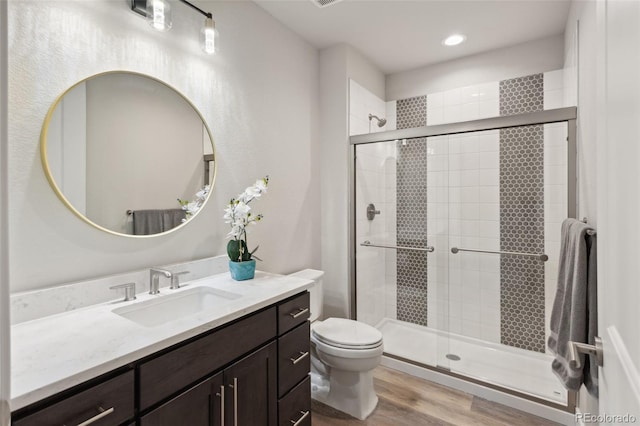 bathroom featuring a shower stall, wood finished floors, vanity, toilet, and recessed lighting