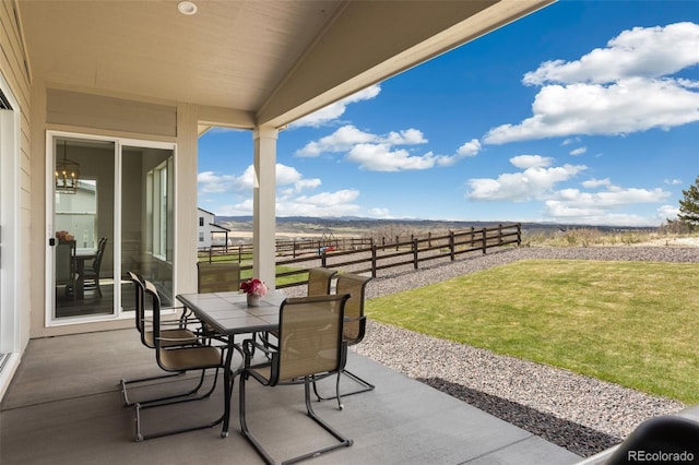 view of patio / terrace with fence, outdoor dining area, and a rural view
