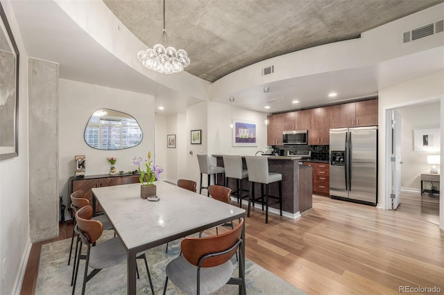 dining room with light hardwood / wood-style flooring and a chandelier