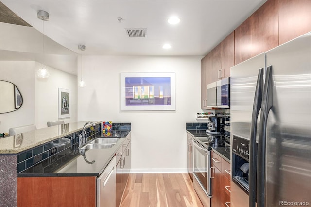 kitchen with sink, a breakfast bar area, stainless steel appliances, decorative light fixtures, and kitchen peninsula