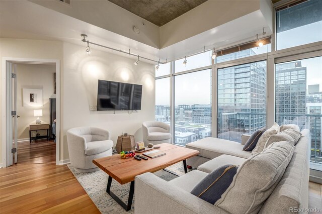 living room featuring track lighting, baseboards, floor to ceiling windows, and light wood finished floors