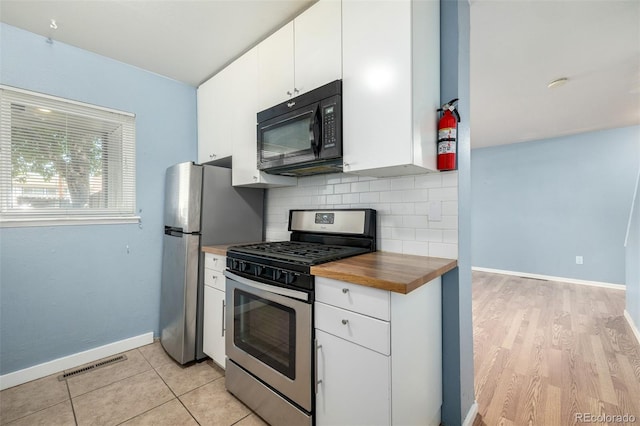 8023 Wolff St Unit C, Westminster, CO 80031 - kitchen with appliances with stainless steel finishes, wooden counters, baseboards, decorative backsplash, and white cabinetry