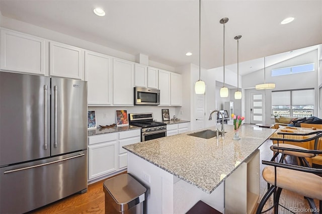 11059 E 25th Dr, Aurora, CO 80010 - kitchen with stainless steel appliances, white cabinetry, a kitchen bar, recessed lighting, and open floor plan