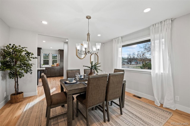 dining space featuring an inviting chandelier and light wood-type flooring