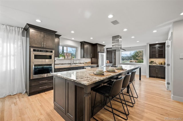 kitchen featuring island range hood, a kitchen island, a healthy amount of sunlight, and sink