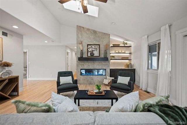 living room featuring hardwood / wood-style floors, a large fireplace, ceiling fan, and lofted ceiling