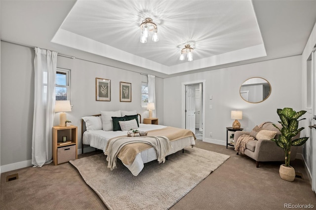 carpeted bedroom with a tray ceiling and multiple windows