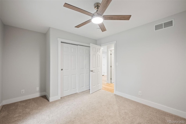 unfurnished bedroom featuring a closet, light colored carpet, and ceiling fan