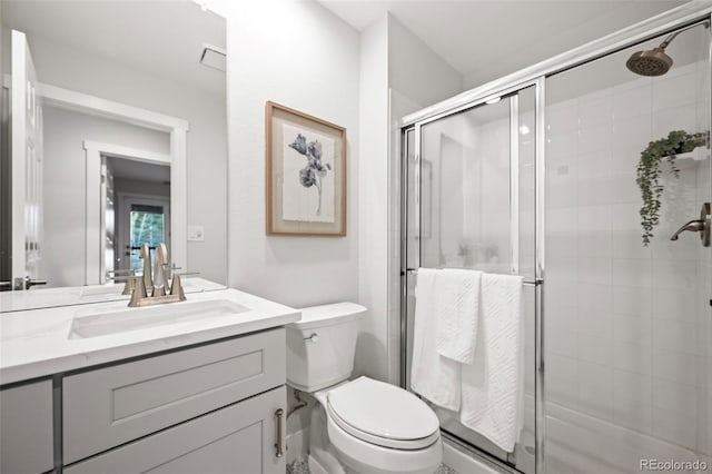 bathroom featuring vanity, toilet, and a shower with door