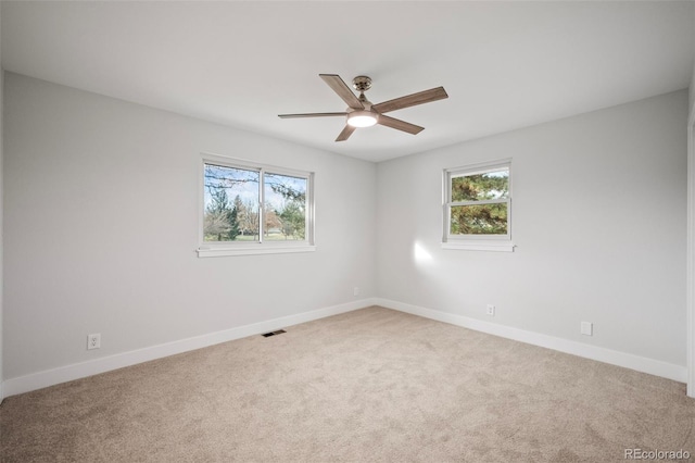 carpeted empty room with a wealth of natural light and ceiling fan