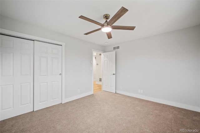 unfurnished bedroom featuring ceiling fan, a closet, and light carpet