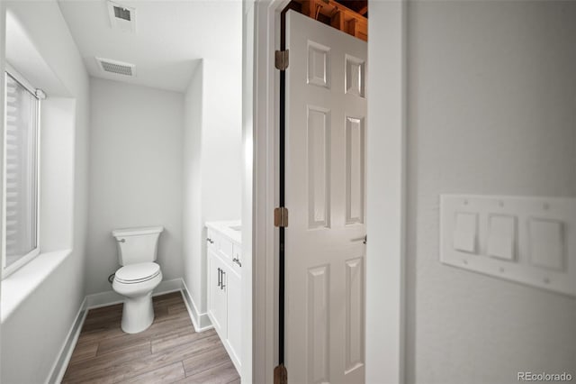 bathroom featuring vanity, wood-type flooring, and toilet