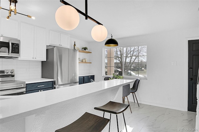 kitchen featuring pendant lighting, decorative backsplash, a breakfast bar, white cabinets, and appliances with stainless steel finishes