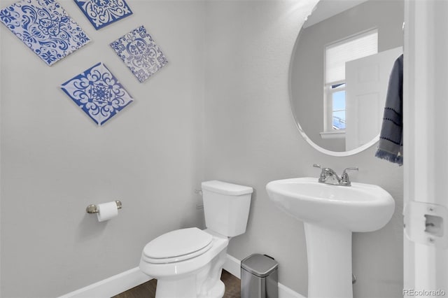 half bath featuring wood finished floors, a sink, toilet, and baseboards