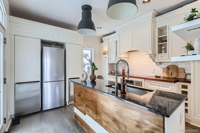 kitchen with backsplash, dark hardwood / wood-style floors, stainless steel refrigerator, and white cabinets