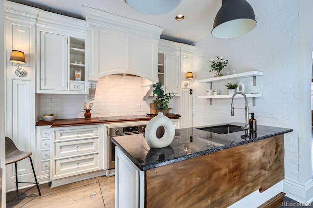 kitchen with cooktop, sink, white cabinets, oven, and backsplash