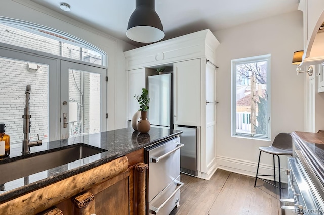 kitchen featuring pendant lighting, sink, white cabinetry, dark stone countertops, and dark hardwood / wood-style floors