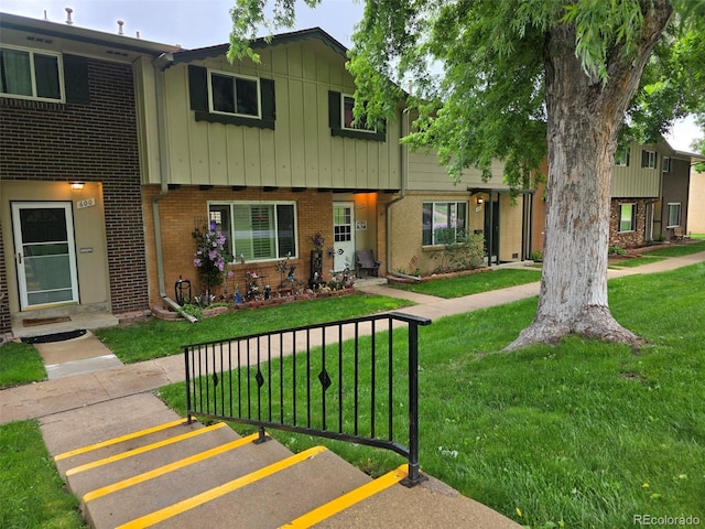 604 S Xenon Ct, Lakewood, CO 80228 - view of property with brick siding, board and batten siding, a front lawn, and uncovered parking
