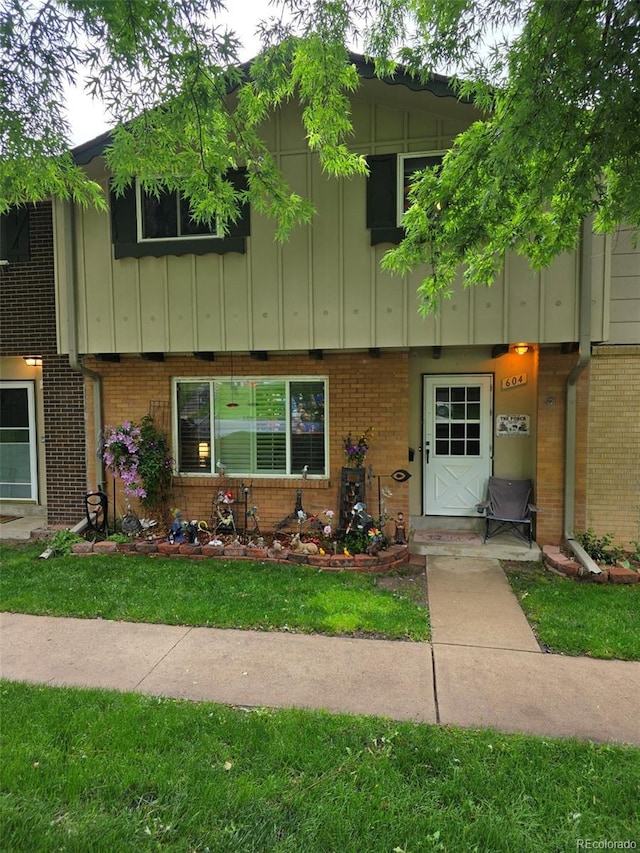 604 S Xenon Ct, Lakewood, CO 80228 - townhome / multi-family property with board and batten siding, brick siding, and a front yard