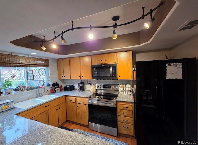 604 S Xenon Ct, Lakewood, CO 80228 - kitchen featuring black appliances, a raised ceiling, light wood-type flooring, tasteful backsplash, and light countertops