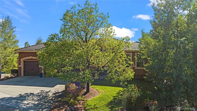12477 Creekhurst Dr, Colorado Springs, CO 80921 - view of property hidden behind natural elements featuring a tiled roof, driveway, stucco siding, and a garage