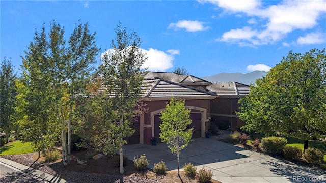 12477 Creekhurst Dr, Colorado Springs, CO 80921 - view of front of property featuring driveway, a garage, a mountain view, and a tile roof