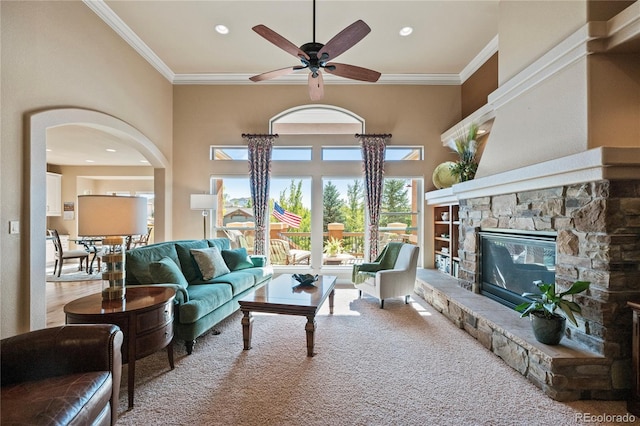 12477 Creekhurst Dr, Colorado Springs, CO 80921 - carpeted living room featuring a ceiling fan, ornamental molding, arched walkways, and a stone fireplace