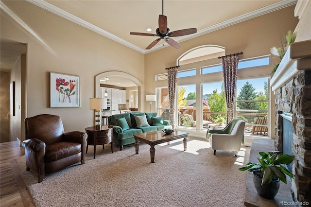 12477 Creekhurst Dr, Colorado Springs, CO 80921 - living room featuring crown molding, a fireplace, arched walkways, a ceiling fan, and a towering ceiling