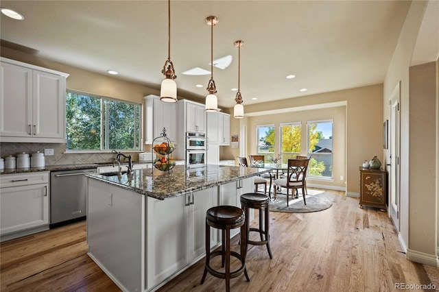 12477 Creekhurst Dr, Colorado Springs, CO 80921 - kitchen with appliances with stainless steel finishes, a kitchen island with sink, light wood-style flooring, healthy amount of natural light, and recessed lighting
