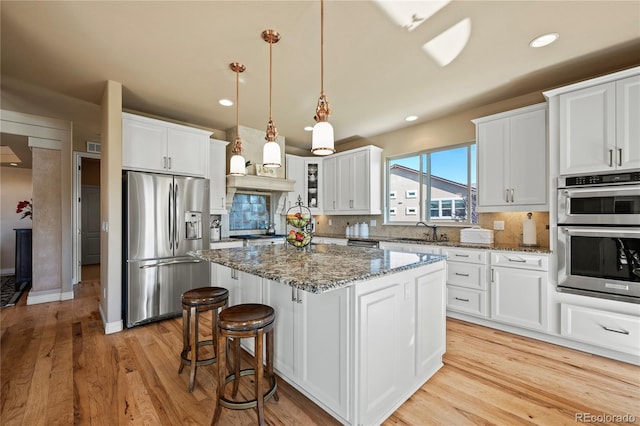 12477 Creekhurst Dr, Colorado Springs, CO 80921 - kitchen featuring appliances with stainless steel finishes, dark stone counters, decorative backsplash, a sink, and light wood-style floors