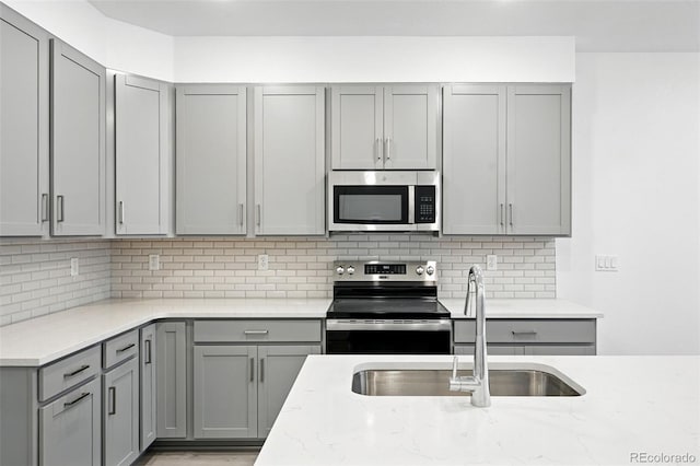17115 W 91st Ln, Arvada, CO 80007 - kitchen with stainless steel appliances, gray cabinets, a sink, and decorative backsplash