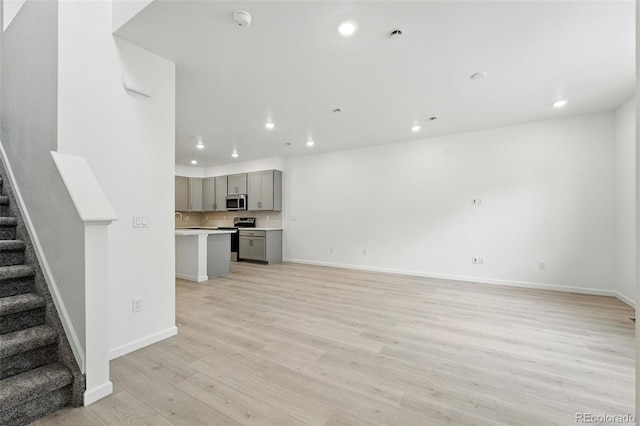 17115 W 91st Ln, Arvada, CO 80007 - unfurnished living room with stairway, recessed lighting, light wood-style floors, and baseboards