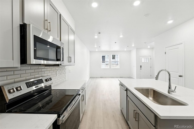 17115 W 91st Ln, Arvada, CO 80007 - kitchen with appliances with stainless steel finishes, a sink, gray cabinets, light wood-style flooring, and open floor plan