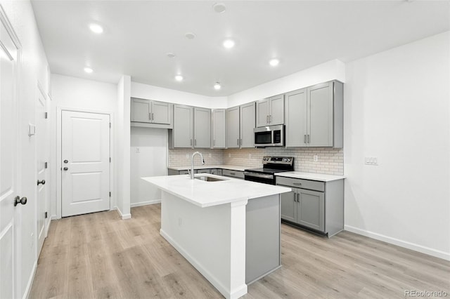17115 W 91st Ln, Arvada, CO 80007 - kitchen with stainless steel appliances, gray cabinetry, a sink, backsplash, and light wood-style flooring