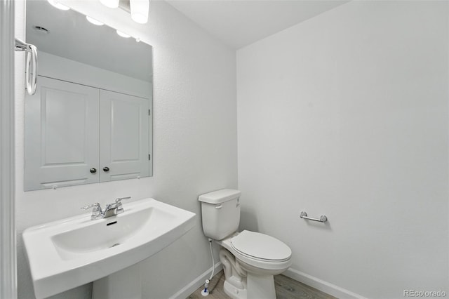 17115 W 91st Ln, Arvada, CO 80007 - half bath featuring baseboards, toilet, wood finished floors, and a sink